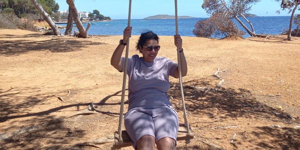 Woman enjoying a swing by the water on a sunny day.