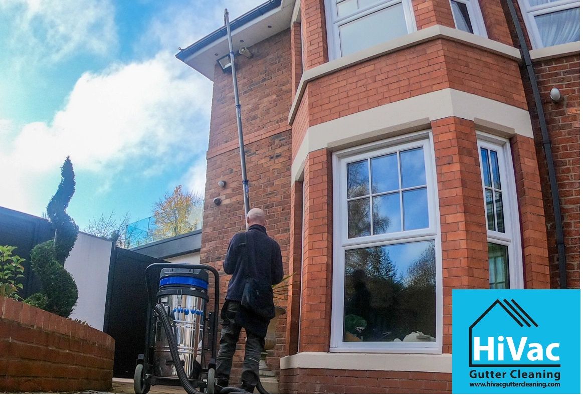 Professional gutter cleaning on a residential brick house with HiVac equipment.