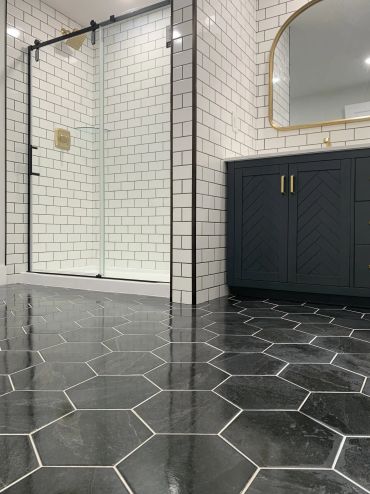 Modern bathroom with black hexagonal floor tiles and white subway walls.