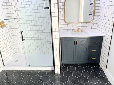 Modern bathroom with black hexagonal floor tiles and white subway tiled walls.