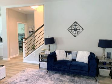 Modern living room with navy blue sofa and decorative wall clock.
