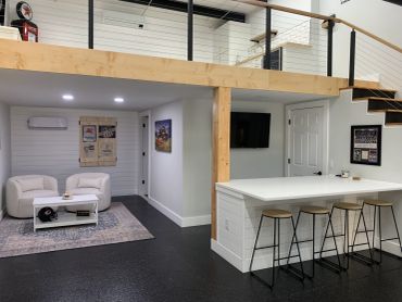 Modern basement with seating area, bar stools, and loft space.