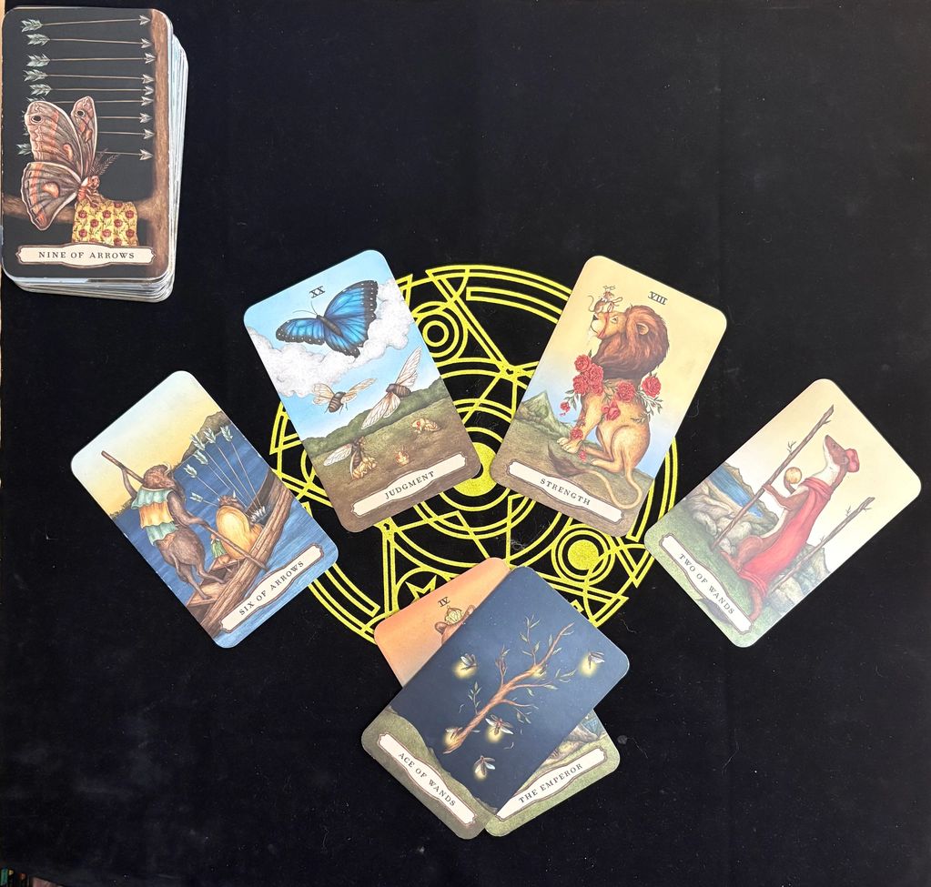 Tarot cards spread on a black cloth with a yellow design.