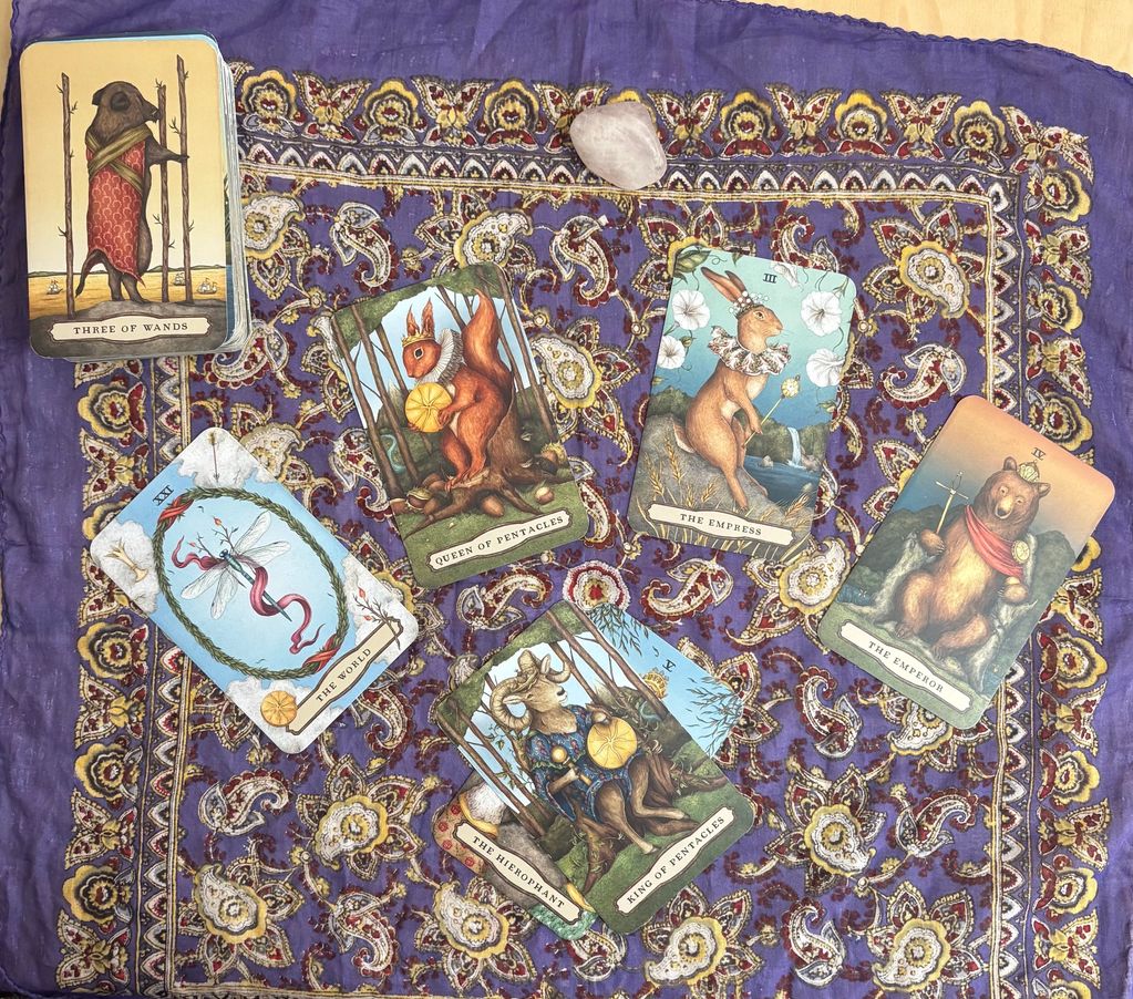 Anthropomorphic animal tarot cards spread on a patterned cloth with a crystal.