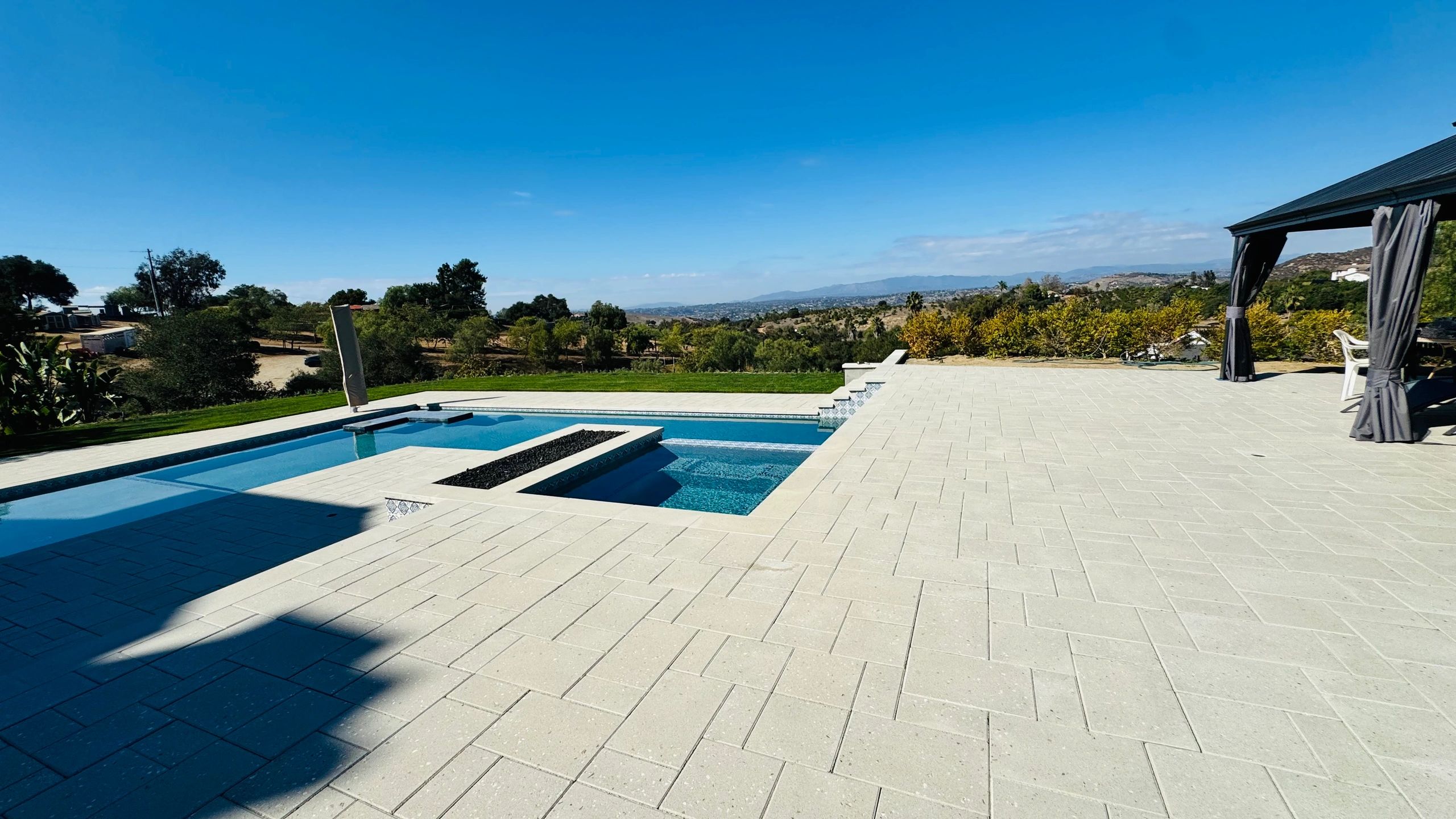 Outdoor pool area with clear blue sky and shaded seating.