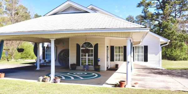 Bright porch with white columns and potted plants on a sunny day.