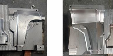 Two metallic industrial mold parts placed on a workbench.