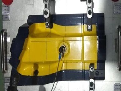 Yellow and black mold used in manufacturing processes with attached sensors.