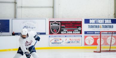 Ice hockey player taking a shot on goal in an indoor rink.