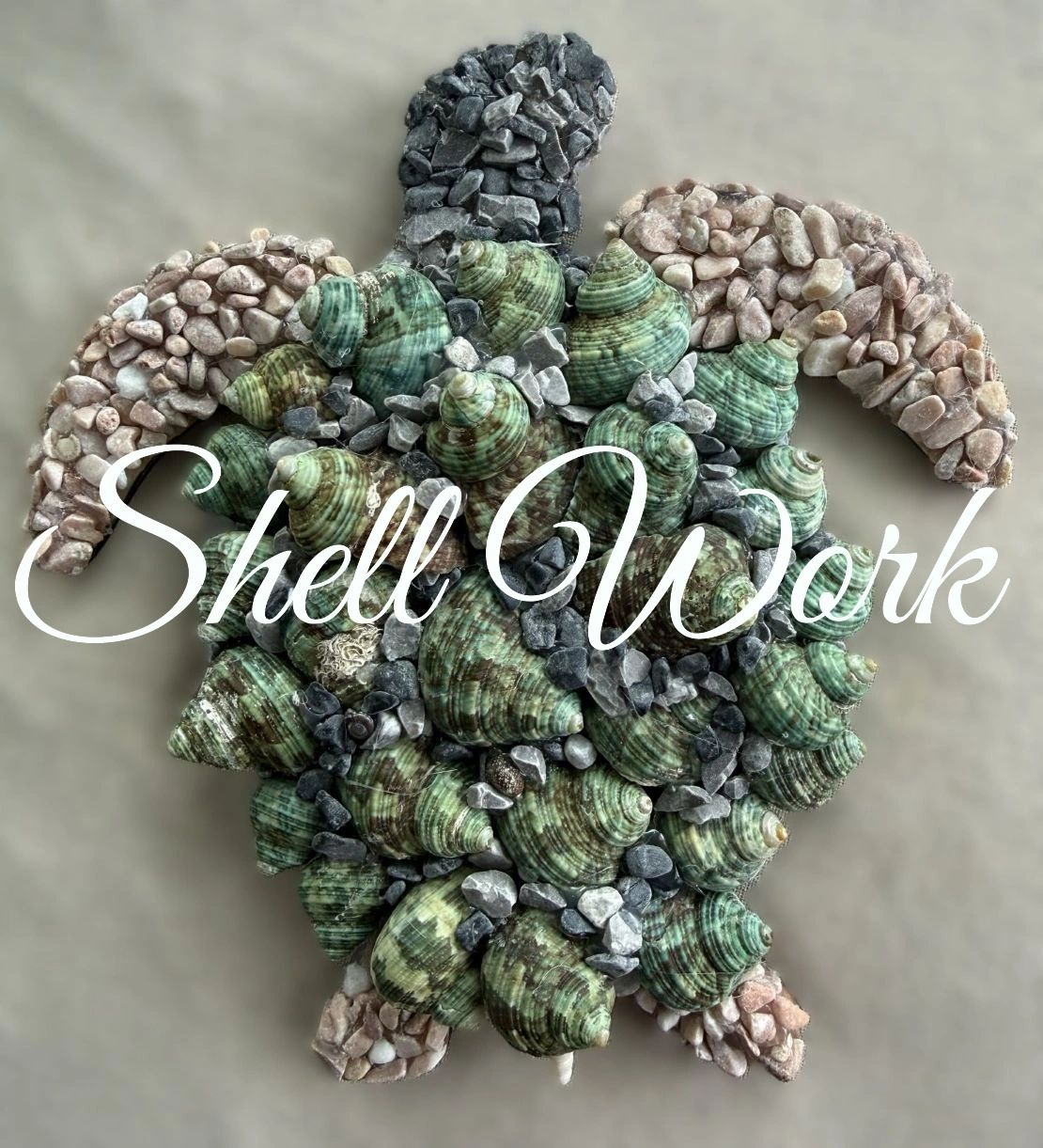 Turtle-shaped mosaic made from green and pink seashells and small stones.