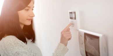 Young brunette woman entering code on keypad of home security alarm