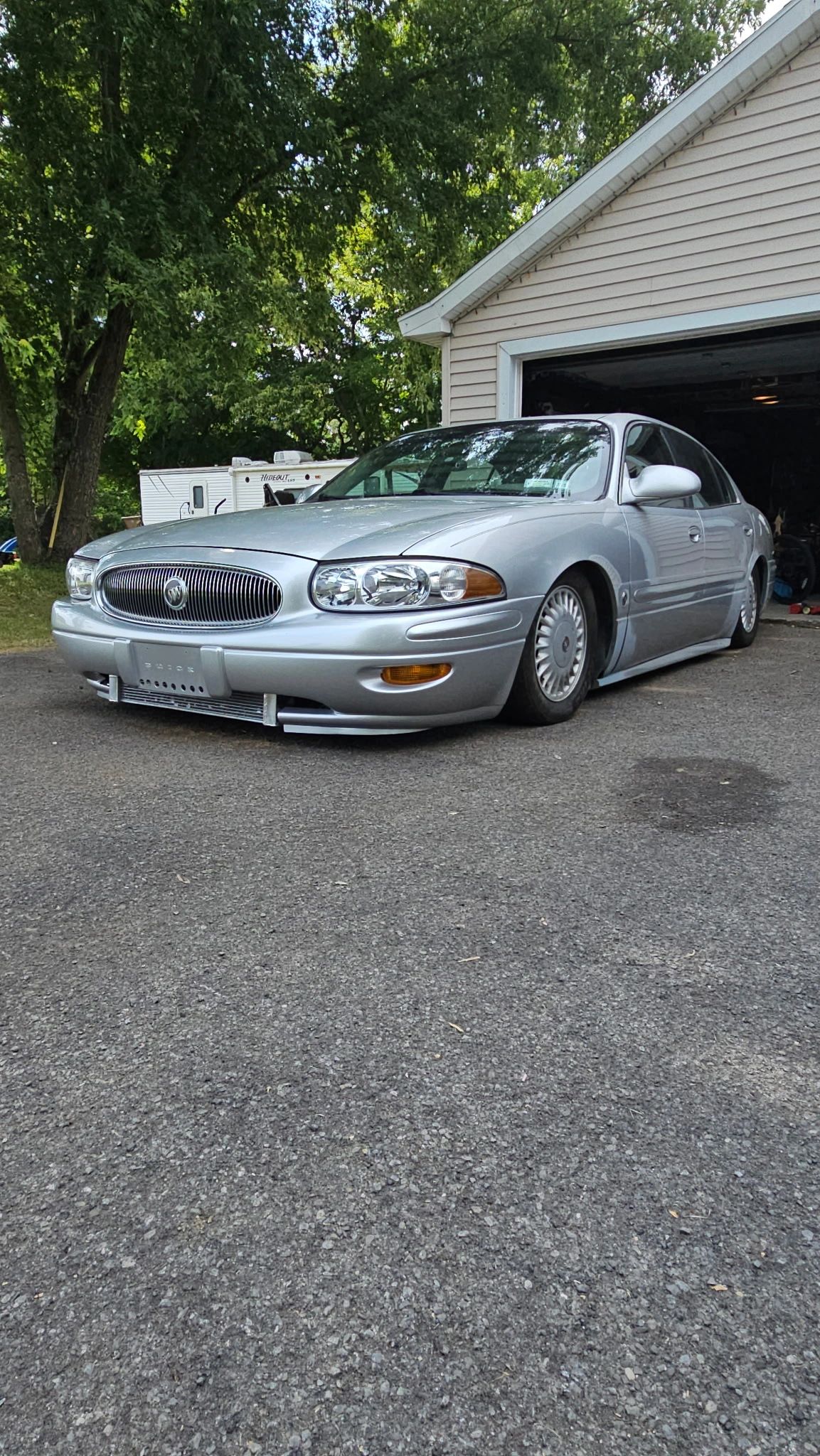 Lowered silver Buick sedan parked by a garage.