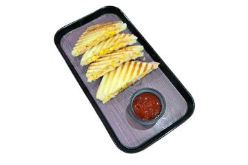 Grilled corn sandwiches with ketchup on a black tray.