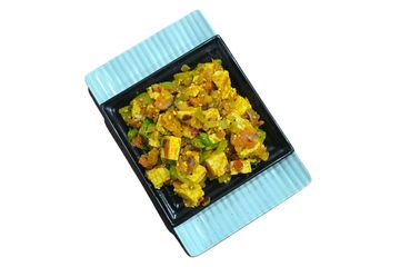 Paneer bhurji with mixed vegetables served in a black bowl on a blue plate.