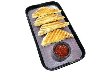 Grilled cheese sandwich triangles served with ketchup on a black tray.