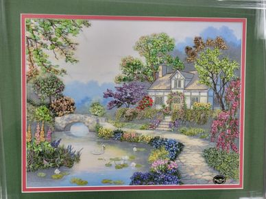 A charming house surrounded by a colorful garden and a pond with a stone bridge.