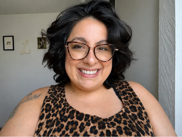 Smiling woman with glasses and animal print top.