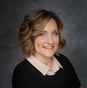 Professional headshot of a smiling woman with short wavy hair.