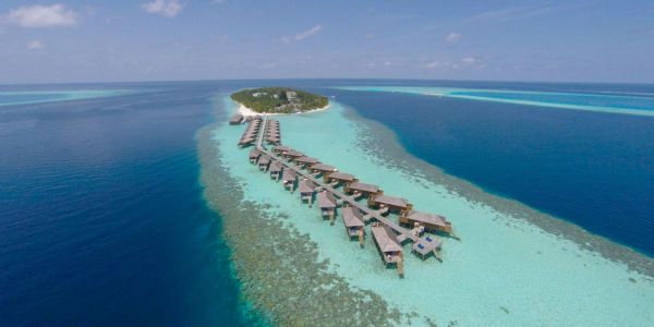 Overwater bungalows on a tropical island surrounded by clear blue sea.