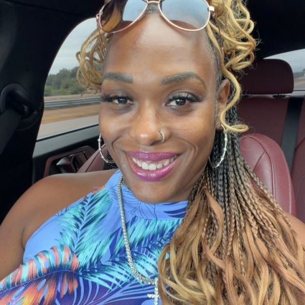 Woman smiling in car with sunglasses on head.