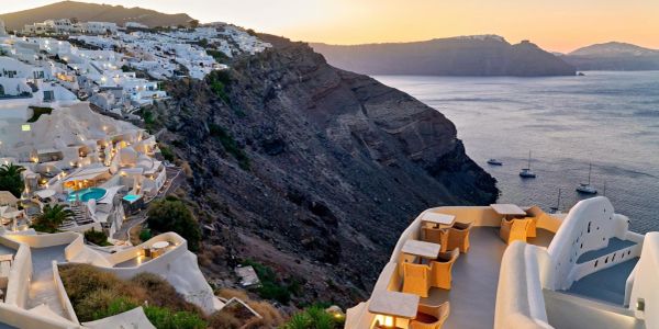 Sunset view of white buildings on a cliff by the sea.