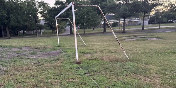 Old, rusty soccer goalpost in a grassy field.