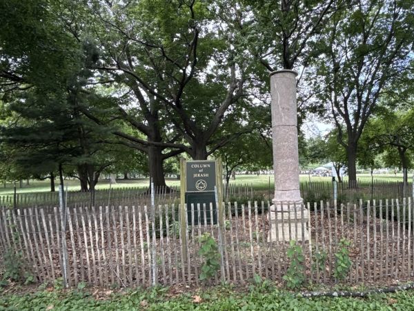 A fenced column monument in a park area.