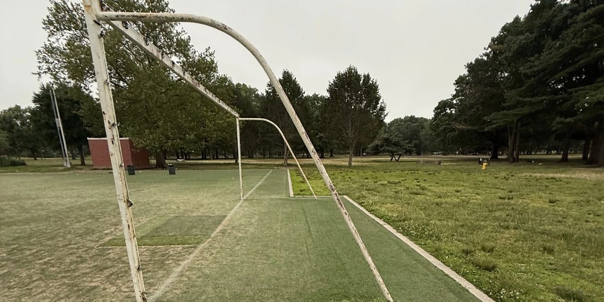 Empty soccer/football goals on a cloudy day in a grassy park.