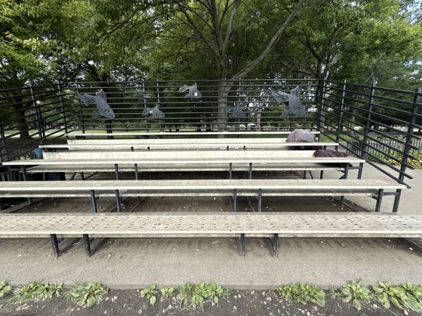 Empty outdoor bleachers with fish decorations on the railing.