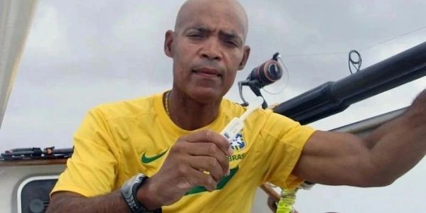 Man in a yellow Brazil soccer shirt holding a fishing lure.