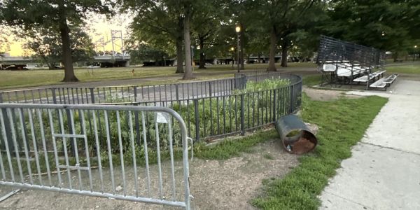 Metal barricade and overturned trash can in park.