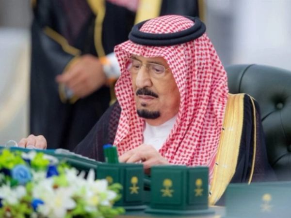 A man in traditional Saudi attire reading documents.