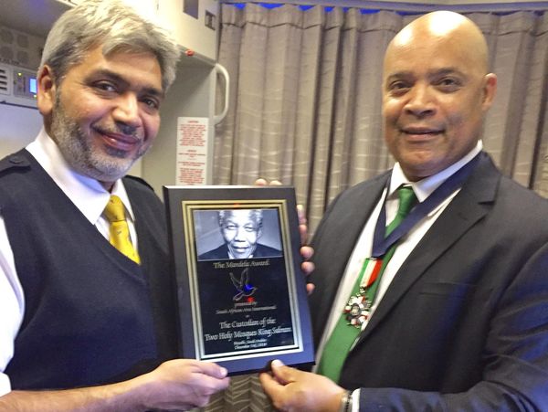 Two men holding a framed Nelson Mandela award plaque.