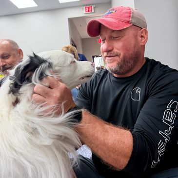 Man in red cap hugging a white and black dog.