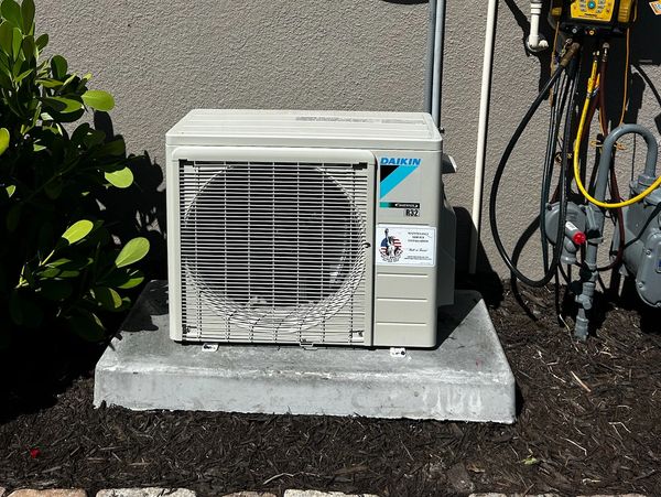 Outdoor Daikin air conditioning unit on concrete slab.