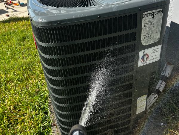 Cleaning an air conditioning unit with water spray.