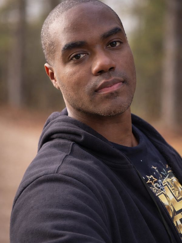 Close-up of a man in a black hoodie outdoors.