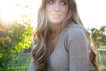 Woman in soft sweater wearing gold jewelry outdoors.