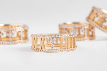 Gold Roman numeral diamond rings on white background.