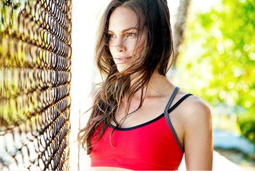 Woman in red tank top standing by chain-link fence