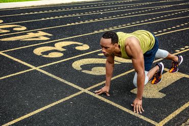 Athlete in yellow preparing on track