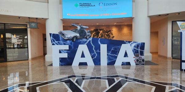 Convention lobby with large FAIA letters and a DeLorean car model.