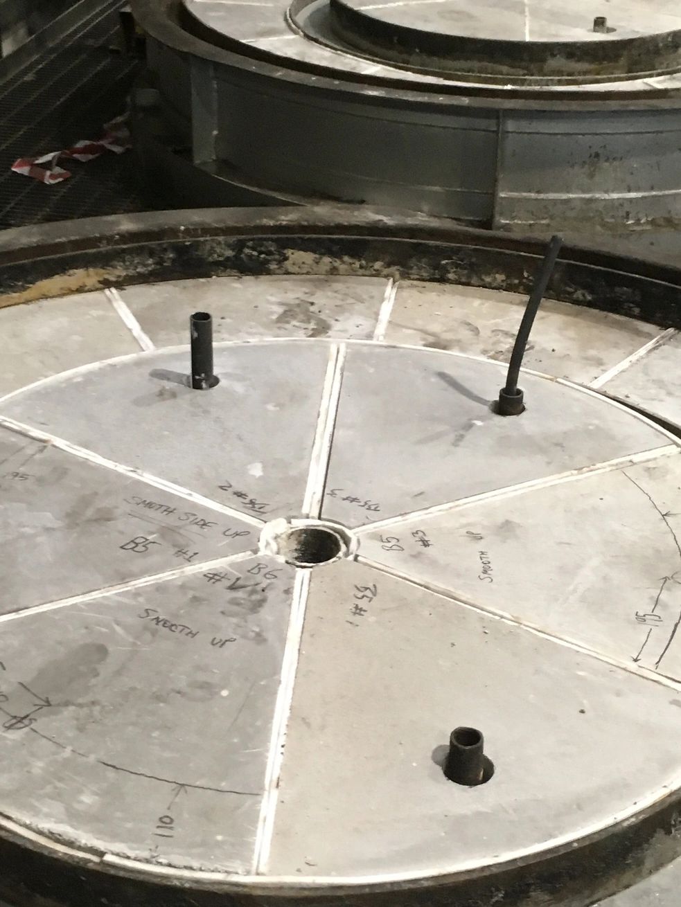 Circular concrete structure with markings and pipes.