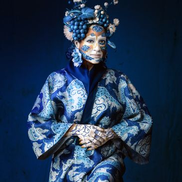 Person in elaborate blue costume and face paint inspired by grapes and floral patterns.