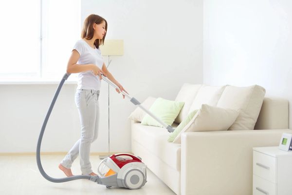 Attractive girl vacuuming, a white couch cleaning