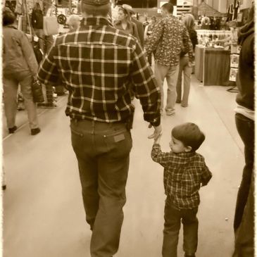 Adult and child holding hands while walking indoors.