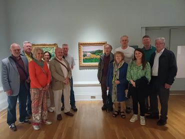 Group of people posing in an art gallery in front of paintings.