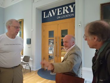 Three men talking inside a gallery space.