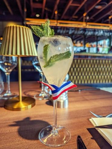 Refreshing cocktail with mint garnish and ribbon.