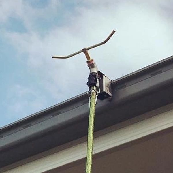 A hose connected to a building's gutter with a handle.